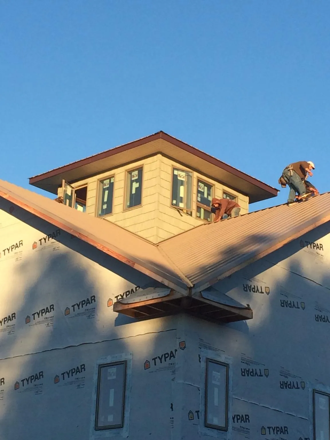 Roofers working around a rooftop cupola on a new metal roof at sunset — Roof Waterproofing in Clio by Roofing Brothers